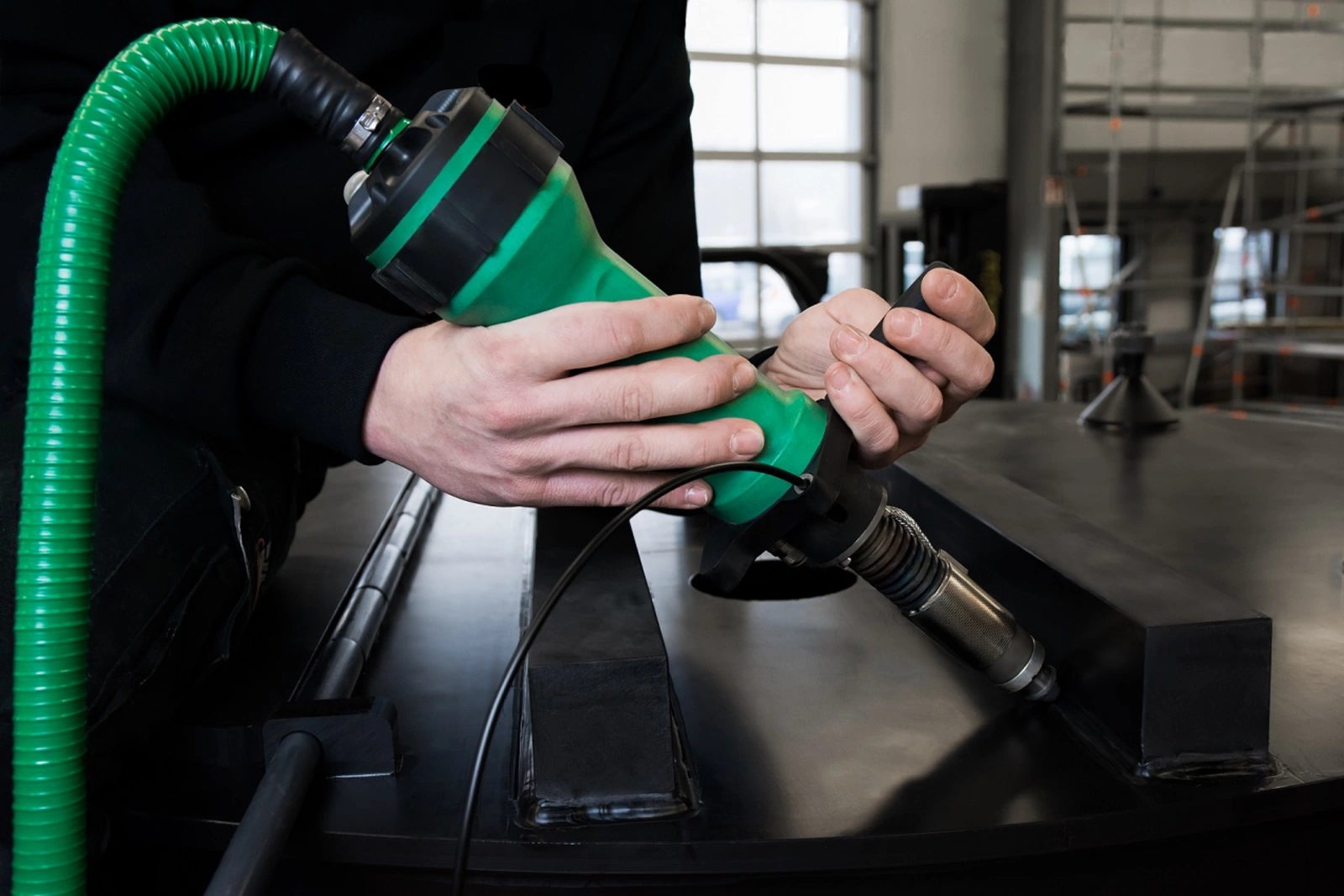 Mann verschweißt Kunststoffteile mit grünem Schweißextruder